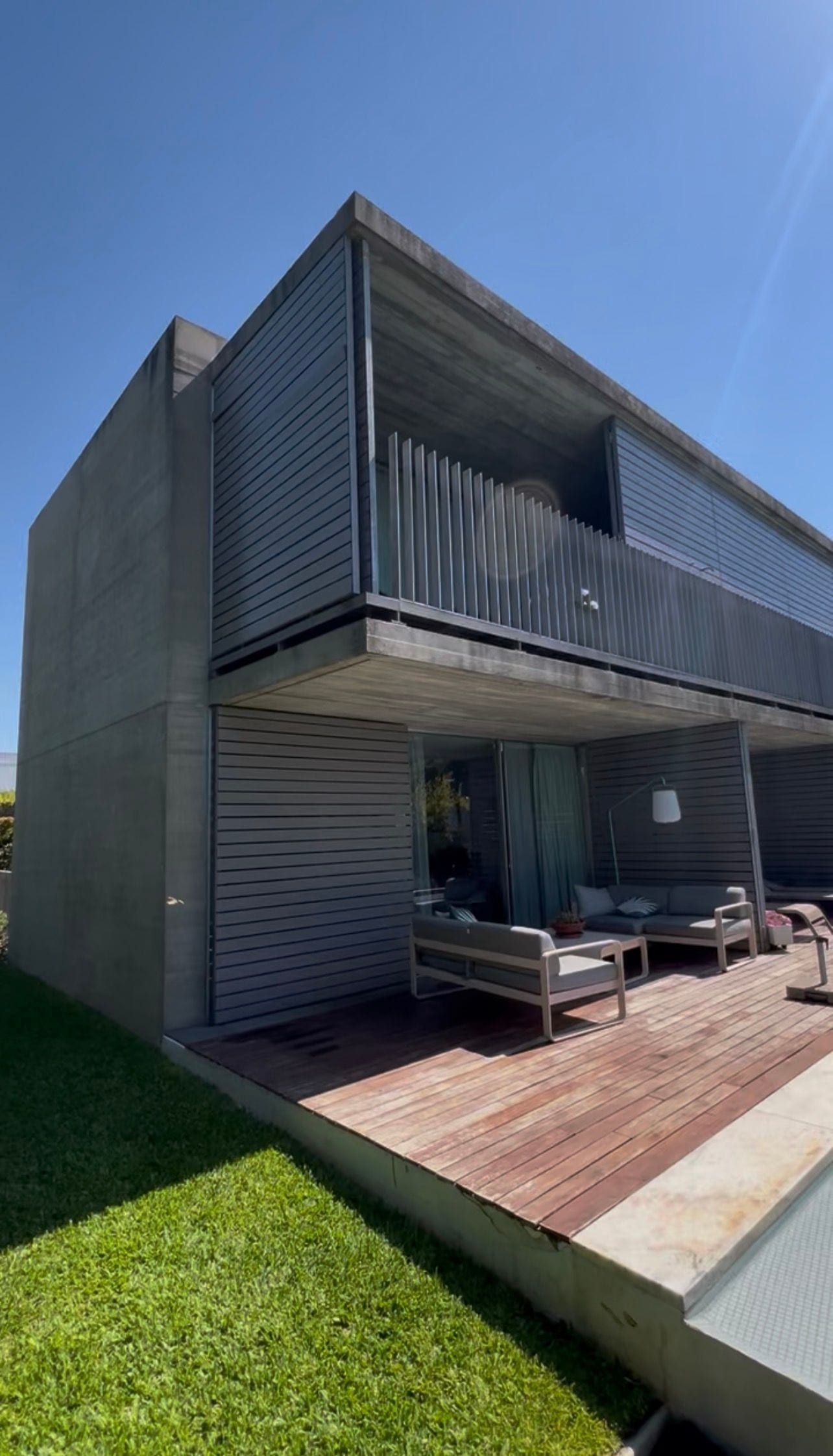 Moradia contemporânea em betão com ripado horizontal, deck de madeira e jardim