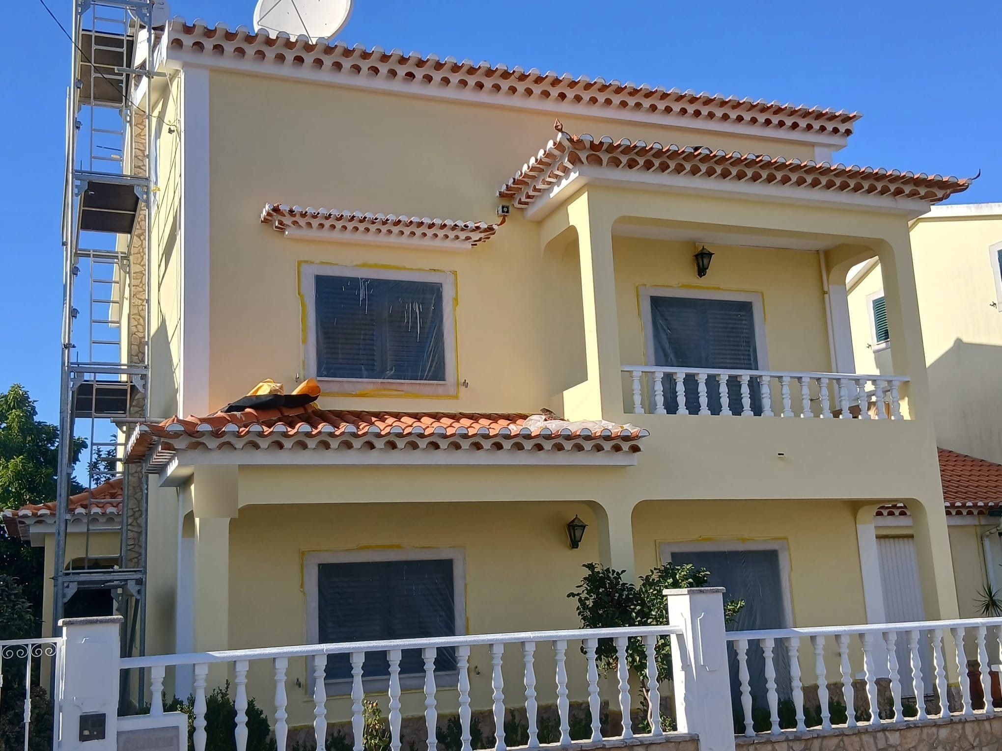 Moradia de fachada amarela em pintura, com as janelas protegidas