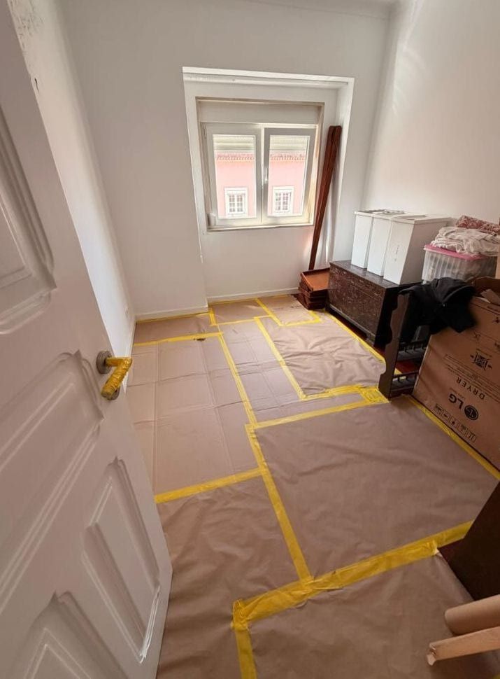 Quarto preparado para pintura, com o chão coberto de papel e fita amarela